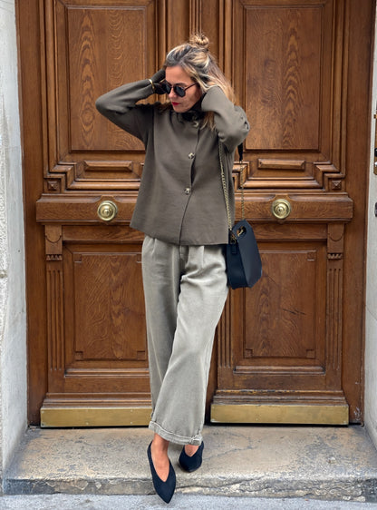 Jean Lumio MYLO kaki clair à coupe large porté avec le gilet Pietra, silhouette entière devant une porte en bois