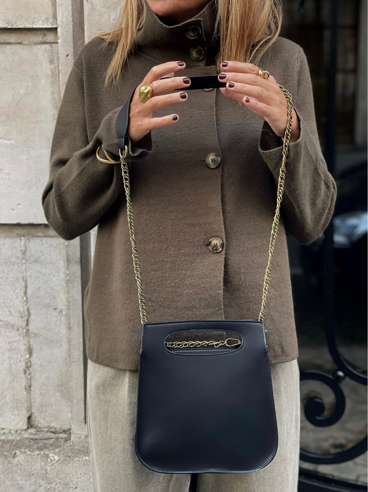 Sac Calvi noir MYLO porté devant, avec sa bandoulière chaîne dorée